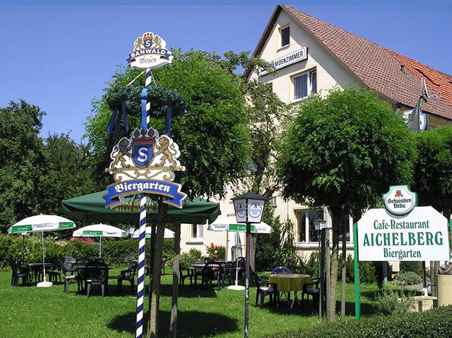 Een 'Biergarten' is een vertrouwd verschijnsel in Duitsland. Het wapen, de vlag en het logo van de brouwer wijzen de weg.